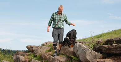 Mann mit Fußheberorthese von ottobock wandert gemeinsam mit Hund in den Bergen.